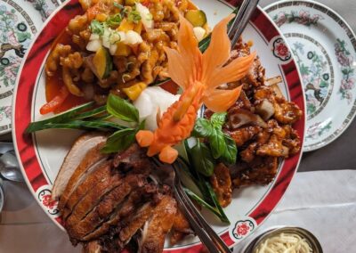 Smaakvol gepresenteerd Chinees gerecht met verschillende vleesbereidingen, kleurrijke groenten, een decoratief wortelsnijwerk op traditioneel porseleinen servies van Restaurant China in Doesburg