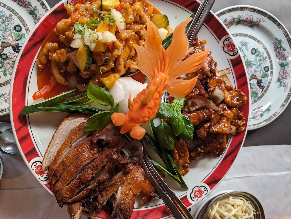 Smaakvol gepresenteerd Chinees gerecht met verschillende vleesbereidingen, kleurrijke groenten, een decoratief wortelsnijwerk op traditioneel porseleinen servies van Restaurant China in Doesburg